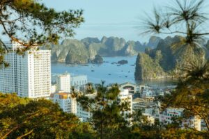 Home A scenic view of Ha Long Bay, Vietnam, showcasing urban buildings against a backdrop of natural karst formations.