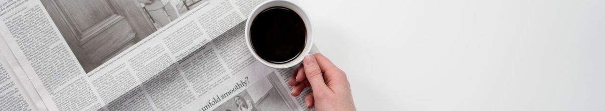Hand holding a black coffee over newspaper, perfect for business and morning themes.
